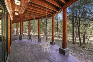 Covered log cabin porch overlooking pine trees